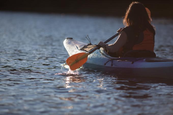 A woman paddles on a body of water.