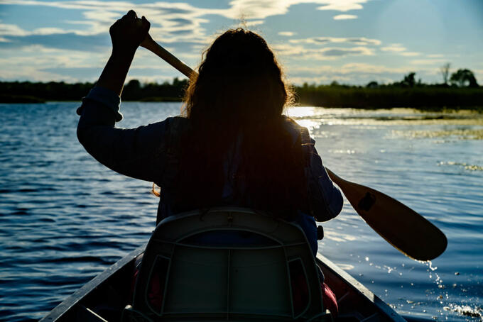 person paddling canoe at sunset