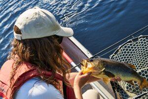 woman on boat holding up largemouth bass
