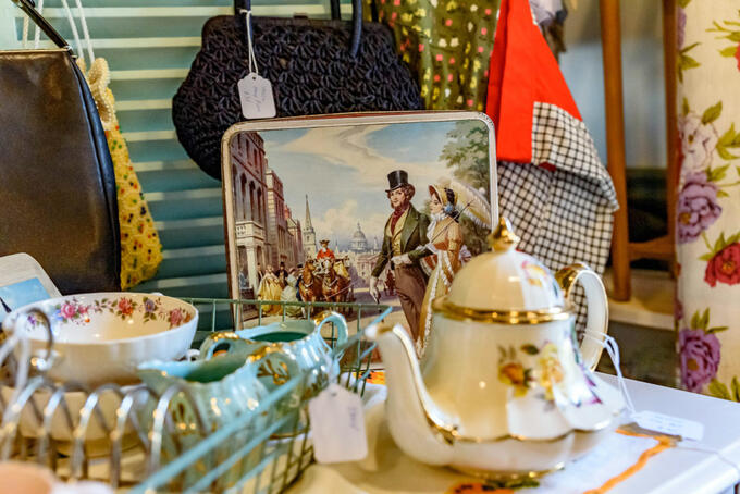 antique teapot, cups, handbags and tray in shop window