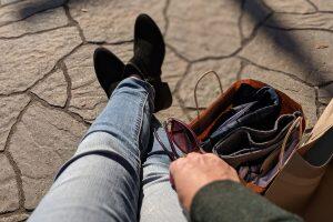 feet, purse and hands holding sunglasses