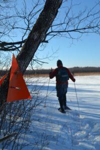 orange triangle trail marker and person snowshoeing in background