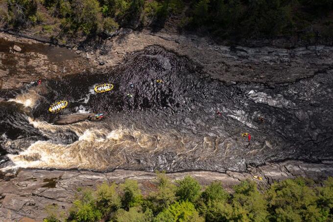 aerial shot of river with rafts on it 