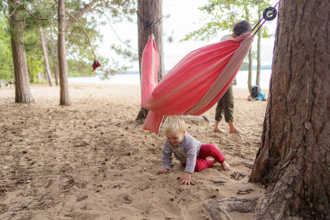 toddler playing in sand under beach hammock 