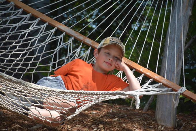 A young boy sits on a hammock.