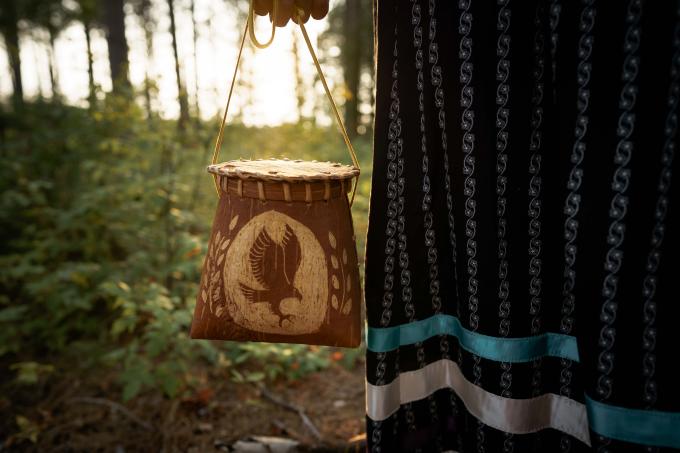 An Indigenous birchbark basket is held by a woman's hand.
