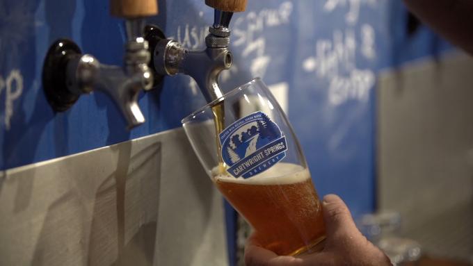 A man pours a glass of Cartwright Springs beer.