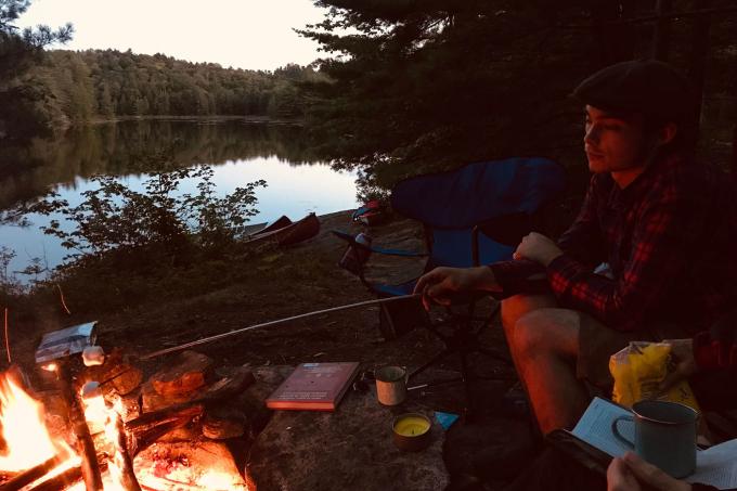 Sitting by the campfire in front of water.