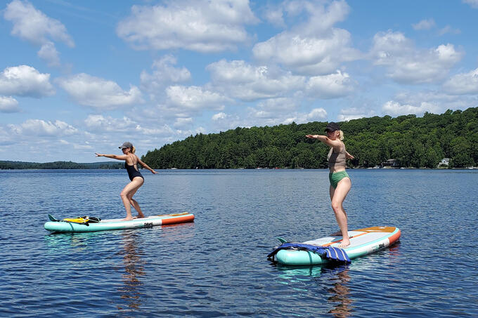Two women stand on paddleboards.