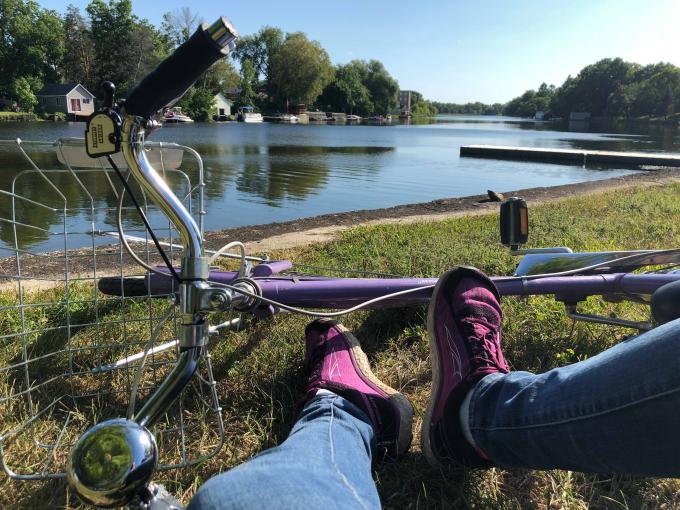 A person sits with a bike on the shores of the Mississippi River.