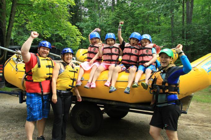 Children in life jackets sit on a raft ready to go in the water.