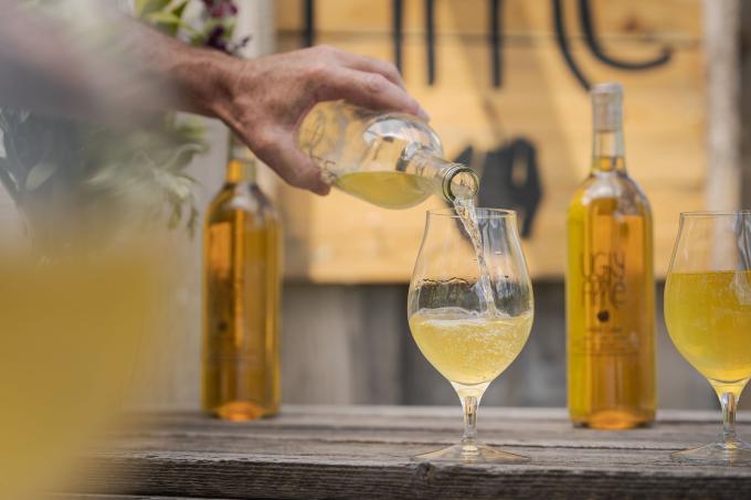 A hand pouring a glass or golden-coloured apple cider