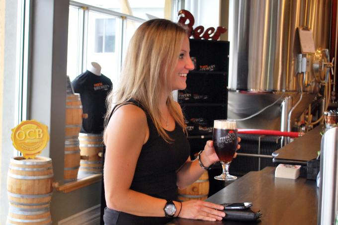 A woman holds a glass of Perth Brewery beer.