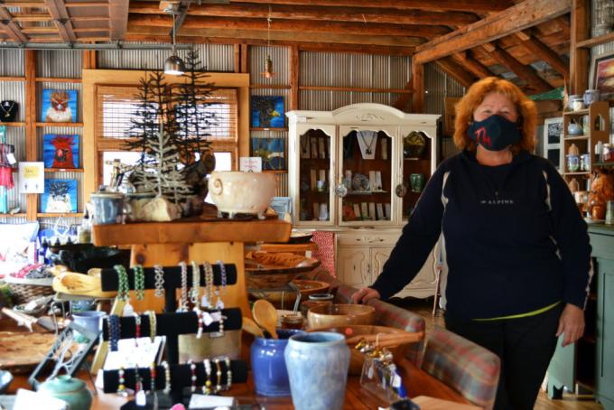 employee standing in the Tinhouse Woodworking and Espresso Bar, surrounded by an array of wooden bowls, pottery, jewellery, art and other merchandise 