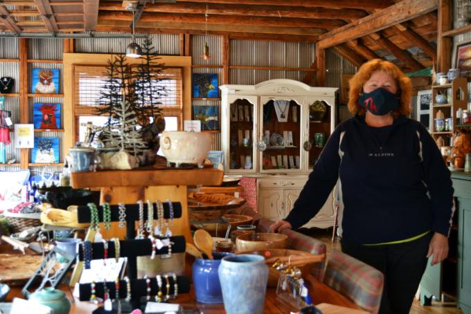 employee standing in the Tinhouse Woodworking and Espresso Bar, surrounded by an array of wooden bowls, pottery, jewellery, art and other merchandise