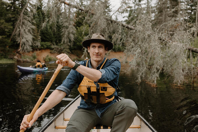 A man paddles a canoe on a river.