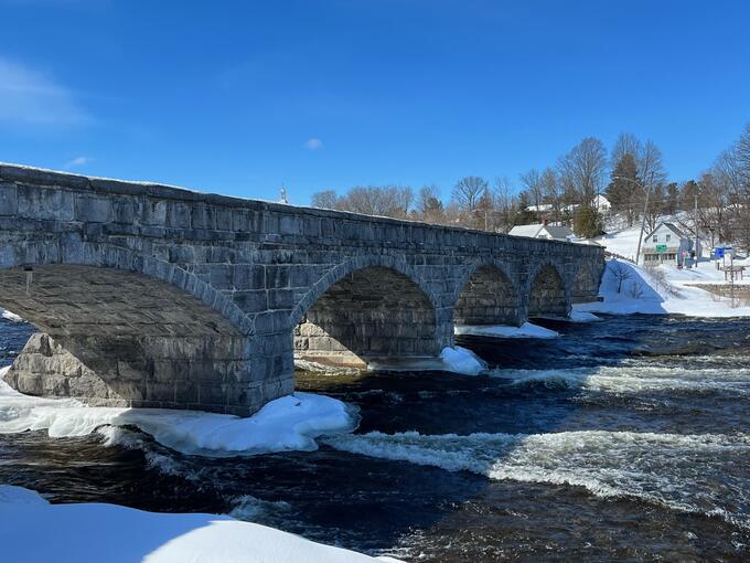 Water rushes beneath a bridge in winter.