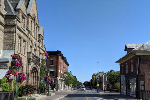 street in Carleton Place; clean streets lined with purple flowers and old stone buildings under blue sky