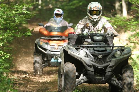 two ATVers driving down forest trail