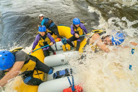 whitewater rafters on rapids with water splashing over side of raft