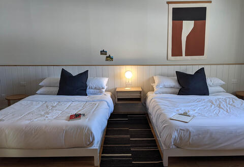 The interior of a hotel room is shown with two beds.
