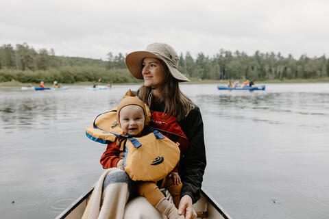 A woman holds a baby in a canoe.
