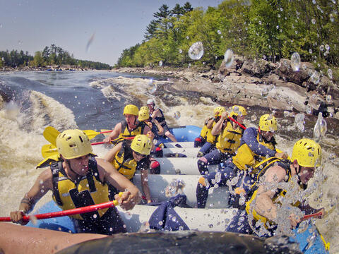A boat full of people experience whitewater rafting.