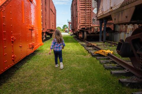 A child walks between railway cars at a museum.