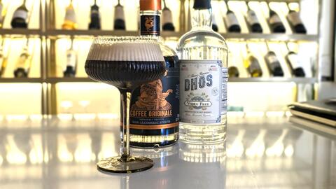 Alcohol-free Espresso Martini on a bar with a bottle of alcohol-free vodka and non-alcohol spirts behind it.