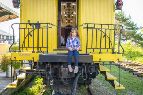 A little girl sits on a caboose 